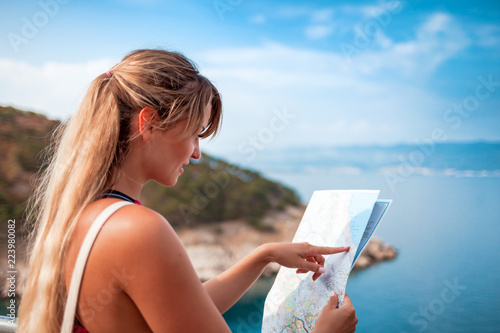 Fotografia Happy young tourist woman with map on sea shore, travel lifestyle