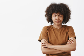 Wall Mural - displeased intense and offended dissatisfied dark-skinned female model with afro hairstyle holding h