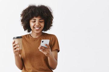 Wall Mural - modern good-looking and stylish african american girl with curly hair holding smartphone and paper c