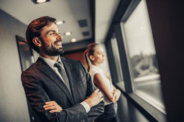 Side view cheerful bearded businessman looking at street while standing near pensive lady