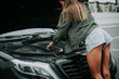 © Yakobchuk Olena - Girl in short shorts turning back to camera while trying to repair car on road. Breakage during trip concept