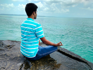 Man sitting on a beach and doing meditation, healthy lifestyle