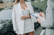 © Yakobchuk Olena - Business lady taking with consultant while standing near vehicle. He making notes on paper during communication outdoor