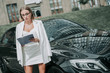 © Yakobchuk Olena - Portrait of concentrated smart business lady in glasses reading information from document while keeping it in hand. She standing near vehicle outdoor