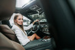 © Yakobchuk Olena - Portrait of smiling businesswoman locating on chair of driver while looking at camera. She locating in vehicle with sunroof and contemporary dashboard