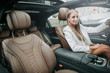 © Yakobchuk Olena - Portrait of smiling business lady locating in cozy vehicle interior on chair of driver. She looking at camera during trip