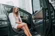 © Yakobchuk Olena - Portrait of beaming pretty lady sitting on chair of comfortable car with open door while looking at camera during rest outdoor