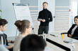 © Seventyfour - Confident businessman standing near the whiteboard and performing for his colleagues at boardroom
