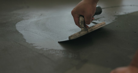 Wall Mural - closeup worker applying micro concrete on the floor with a trowel