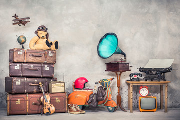retro teddy bear toy in aviator's hat, wooden plane, aged classic travel valises, globe, children pe
