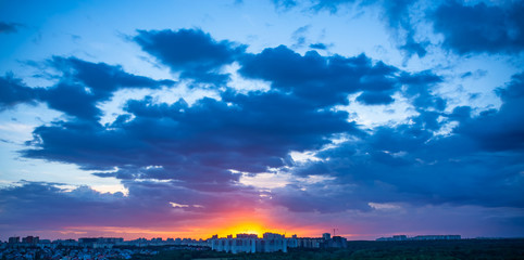 Wall Mural - Dramatic sunset over evening city with bright blue clouds and sky, beautiful panorama