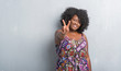 © Krakenimages.com - Young african american woman over grey grunge wall wearing colorful dress showing and pointing up with fingers number two while smiling confident and happy.