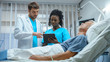 © Gorodenkoff - In the Hospital, Senior Man Sleeps in the Bed, Doctor and Nurse Standing in the Ward, Using Tablet Computer. Technology Helps Cure Patients, Modern Hospital Ward.