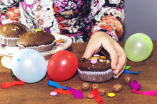 Woman Hand Eating  Chocolate Arabic Homemade Cupcake, Madeleine With Colorful Ballons And Smarties. Birthday Party 