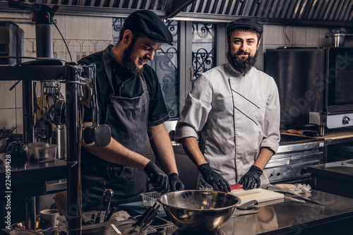Fotomural Two smiling bearded cooks dressed in uniforms preparing sushi in the kitchen