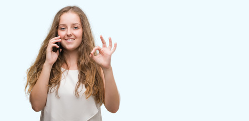 Poster - Young blonde woman using smartphone doing ok sign with fingers, excellent symbol