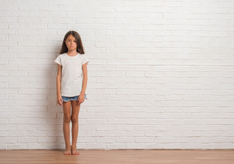 young hispanic kid stading over white brick wall depressed and worry for distress, crying angry and 