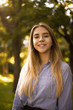 © Sunrise Team - Happy cheerful girl student posing in the park outdoors on grass looking camera.