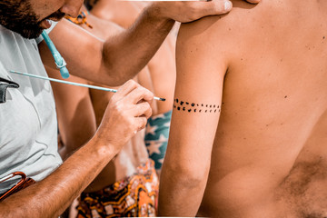 Wall Mural - Creating a tattoo on a hand with paint and brush. Body art.