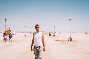 Wall Mural - Young man walking down the desert in the middle of the nowhere between lamp posts. 