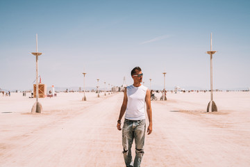 Wall Mural - Young man walking down the desert in the middle of the nowhere between lamp posts. 