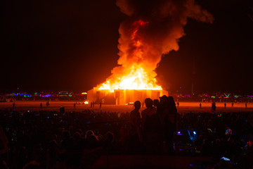 Wall Mural - Huge fire place in the middle of the desert with people watching all around it.