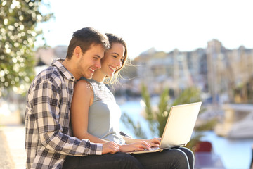 Wall Mural - Couple using a laptop in a sunny coast town