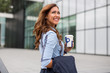 © Marko - Beautiful young businesswoman holding a coffee to go in front of an office building
