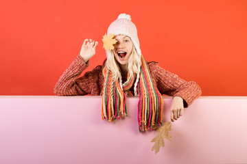 Wall Mural - Surprise woman playing with leaf and looking at camera. Happy girl Having fun. Isolated object on pink background. Autumn time. Season and autumn holiday.