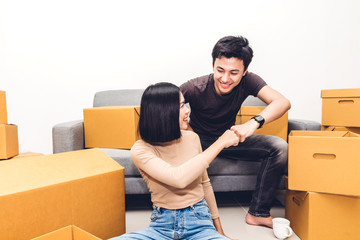 Wall Mural - Happy young couple giving high-five and unpacking box and moving into their new home.House moving and real estate concept