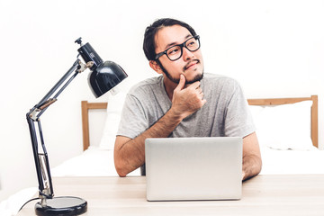 Happy man relaxing and using digital laptop computer on the bed at home.man checking social apps and working.wireless technology concept