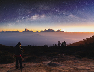 Wall Mural - traveller taking photograph of landscape sunrise and sky full of stars in dawn