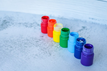 rainbow Gouache or acrylic paints in jars on white grunge background, selective focus