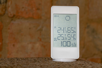 Wall Mural - Home weather station device with weather conditions inside and outside on a brick background.