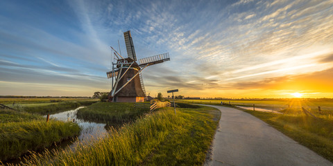 Wall Mural - Wooden windmill with cycling track at sunset