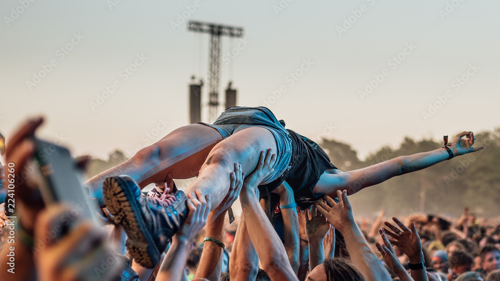 The audience carry the young woman on their hands during rock concert. - obrazy, fototapety, plakaty 