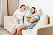 © oksix - Couple sitting on couch at home in the living room.