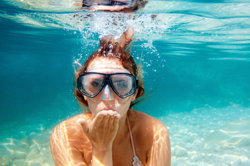 Wall Mural - Woman underwater snorkeling in the clear tropical water and blowing a kiss