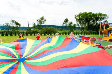 Canvas Print - rainbow parachute waived by kids in the summer outdoors