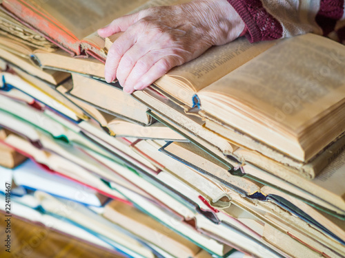 Fotografia, Obraz old female hand is lying on stack of book