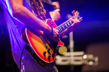 Guitarist Playing On Electric Bass Guitar On Stage. Colorful, Soft Focus And Blur Background