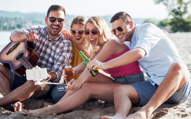 Wall Mural - Group of friends enjoying picnic on the beach. Lifestyle, vacation, relationships concept