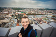 Male tourist stands on top of european city hall with view of historical center of Lviv
