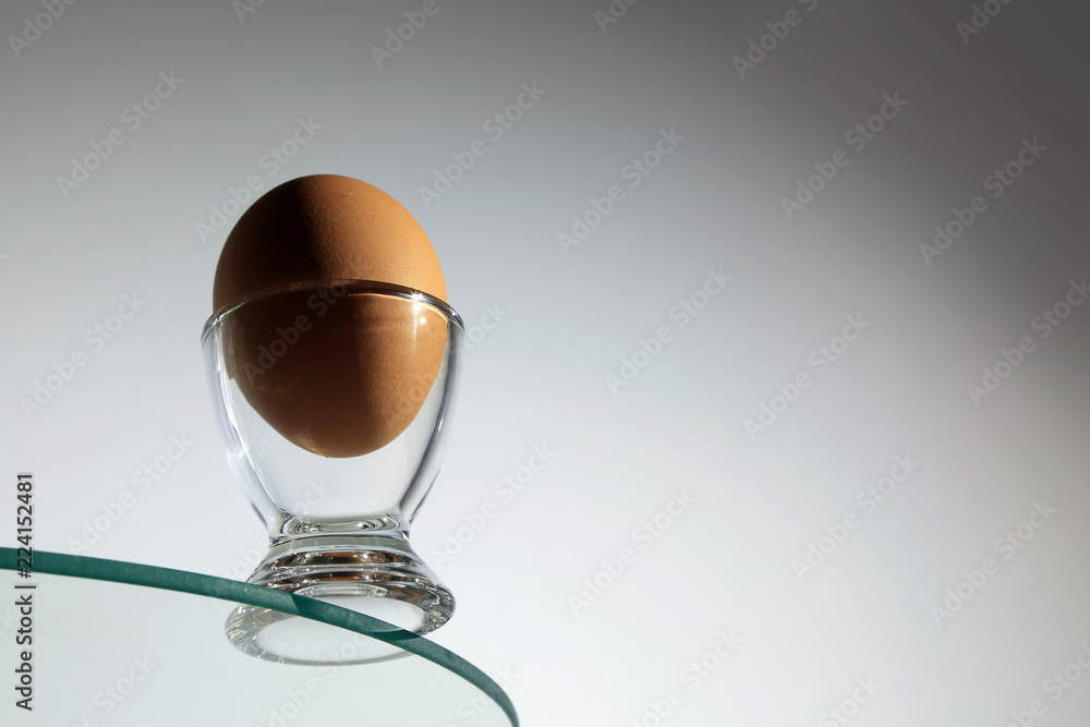 Jajko kurze w szklanym kieliszku na krawędzi szklanego okręgu. - obrazy, fototapety, plakaty 