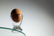 Jajko kurze w szklanym kieliszku na krawędzi szklanego okręgu.