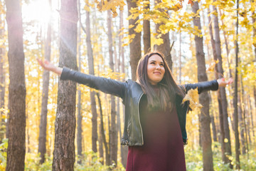 Autumn, fun and delight concept - Young beautiful woman in leather jacket throwing bouquet of leaves