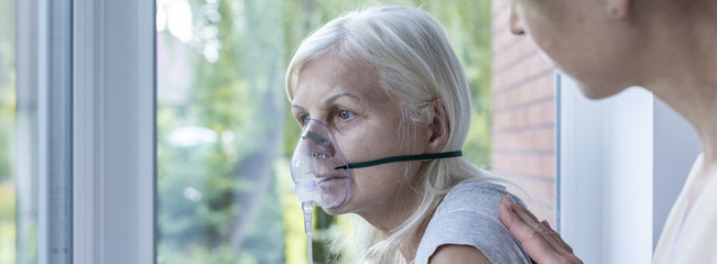 panorama of weak senior woman with oxygen mask on face in the nursing house