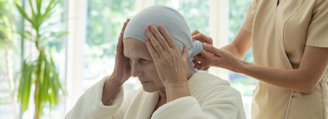 Sticker - Panorama of caregiver putting scarf on elderly woman's head during chemotherapy