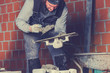Real construction worker bricklaying the wall using tools.