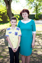 Young, beautiful woman hugging boy, teenager in strict clothes. Mom and son.